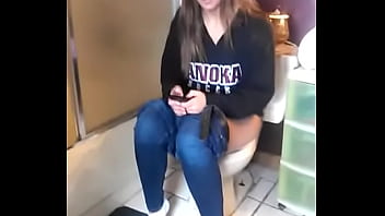 Menina no banheiro enquanto usa o telefone