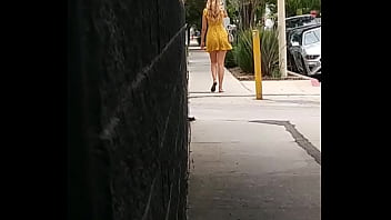 セクシーな黄色のドレスを着て通りを歩いている率直な超セクシーなブロンド