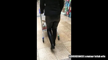 Femme dans un centre commercial - cuissardes, gants en latex, masque et pantalon en cuir (vidéo via smartphone)