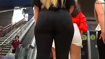 Woman is standing on the escalator and I'm filming her ass