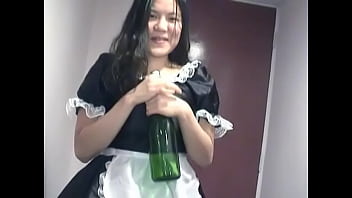 Young Asian girl dressed as a maid indulges herself with a bottle of champagne on camera for you