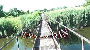 Summer nostalgia. Dressed in sun. Sexy naked woman MILF walks on hanging bridge of river. Nudists. Naturists. Nude beach. Music erotic clip.