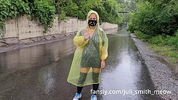 giovane donna in impermeabile giallo lampeggia figa all'aperto sotto la pioggia