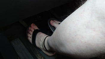 Barefoot in flip flops **driving a car**